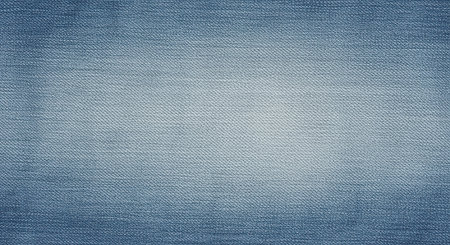Blue denim textured fabric background with faded center and visible woven pattern for fashion or textile design themes.の素材
