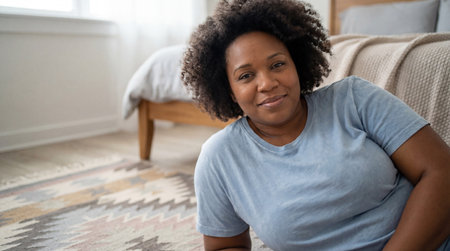 Smiling woman relaxing on cozy bedroom floor with textured rug in natural light, enjoying peaceful morning at home and casual comfort.の素材