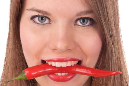 The beautiful girl holds chili pepper in her teethの写真素材