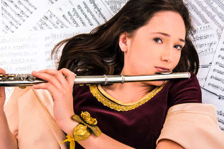 the girl in a brocade dress with a flute on the background of the notesの写真素材