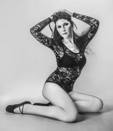 black-and-white photo of a beautiful fashion girl with beautiful legs sitting dressed in a lace bodysuitの写真素材