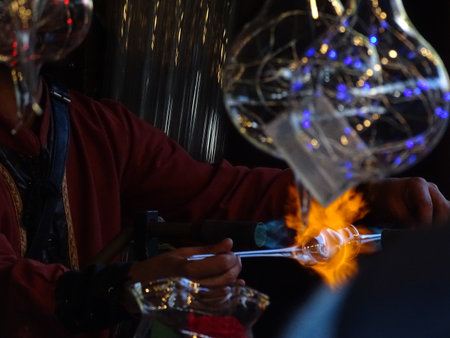 A blacksmith makes a glass lamp with a torch and sparks.