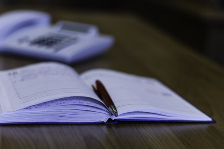 notebook, pen and phone on the tableの写真素材