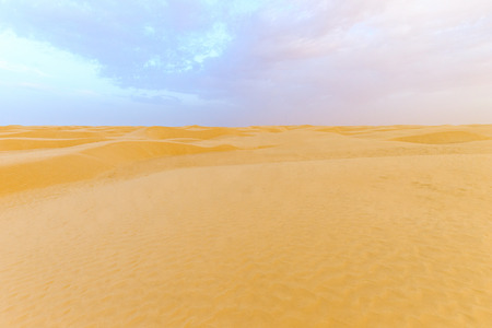 Landscape of Sahara desert with cloudly sky at evening. Sand dunes, Tunisia.