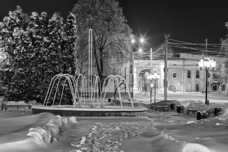 Garland fountain in the winter park at night with decorations, lights and trees. Monochrome image. Landscape.の写真素材