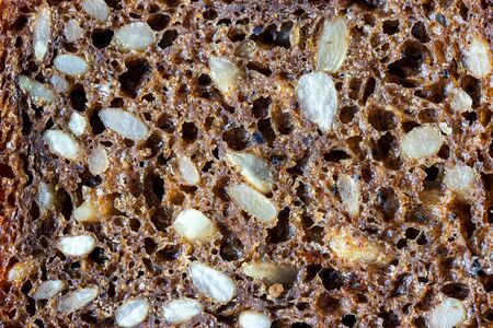 Black bread texture with sunflower seeds. Healthy food background. Abstract.