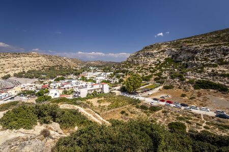 The sea coast and mountains of Matala on a clear summer sunny day with cliffs in the foreground and a cloudy sky in the background. Crete, Greece.の写真素材