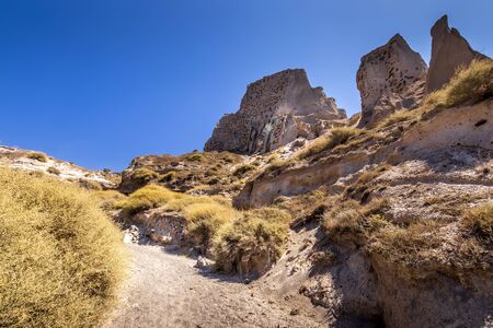 Canyon mountains on Vlychada beach on a sunny summer day with footpath and blue sky background. Santorini island, Greece.の写真素材