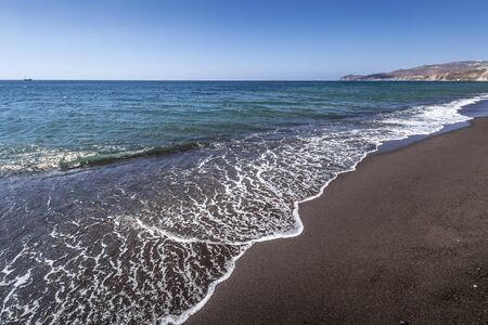 Sea surf on the beach with black volkanic sand. Close-up. Abstract background. Landscape. Vlihada,...