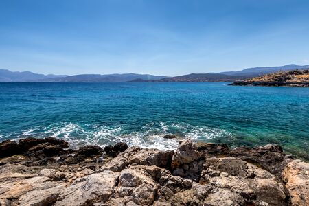 Agios Nikolaus coastline on a sunny day with clear turquoise sea and cliffs. Crete, Greece, Aegean...
