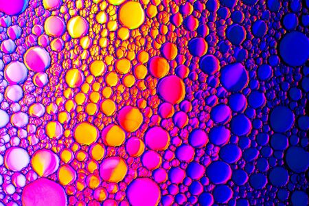 Top view on a colorful drops of oil on the water. Rainbow or spectrum colored circles, ovals....
