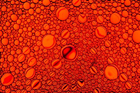 Top view on colorful drops of oil on the water. Circles and ovals. Abstract red background for design.の写真素材