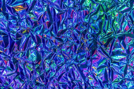 Texture of crumpled aluminum kitchen foil with reflected violet and green light. Colorful abstract...