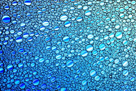 Top view on colorful drops of oil on the water. Blue circles and ovals. Abstract bright background...