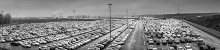 Volkswagen, Russia, Kaluga  - NOVEMBER 21, 2019: New cars parked in a distribution center on a cloudy rainy day in the autumn, a car factory. Panorama of a parking in the open air. Black and white photo.のeditorial素材