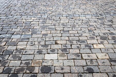 Top view on paving wet stone road after rain. Old pavement of granite texture. Street cobblestone sidewalk. Abstract background for design.の写真素材