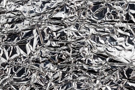 Texture of crumpled aluminum kitchen foil. Silver abstract background for design with copy space for...