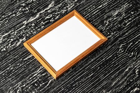 Photo frame on a black wooden table. Abstract background for design. Art stylized baner or mock up with copy space for a text.の写真素材