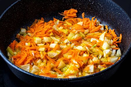 Stewed vegetables in a pan. Cooking process. Vegan food. Fried onions and carrots.の写真素材