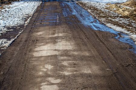Dirty asphalt road with tire tracks in spring. Off-road.の写真素材