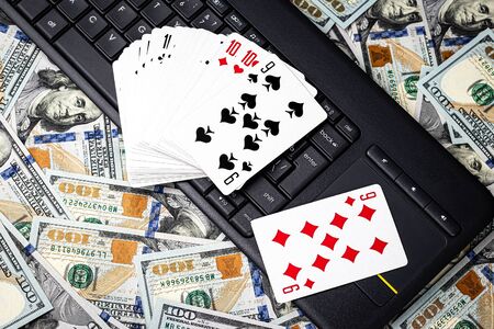 Hundred dollar bills, a deck of playing cards and a black keyboard. Concept of card games, casino or poker online. Online gambling.の写真素材