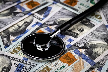 Stethoscope on the background of one hundred dollar bills. The concept of the expensive cost of healthcare or financing medicine.の写真素材