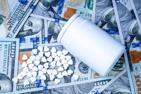 Heart-shaped pills on the background of hundred-dollar bills. The concept of the expensive cost of...