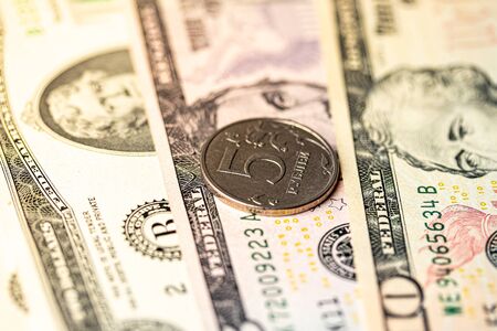 Five-ruble coin on the background of dollar bills. Exchange rate concept.