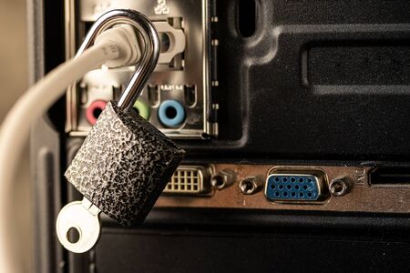 Opened lock hanging on a network cable plugged into a computer. The concept of opening access, unlocking the Internet or hacking anti-virus protection or firewall by hackers. Theft of personal data.の写真素材