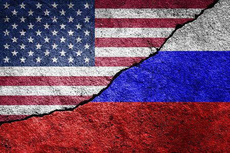 The crack between the Russian Federation and USA flags on the concrete wall. The concept of sanctions, trade war, the deterioration of diplomatic relations, confrontation and severance of agreements.の写真素材