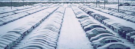 New cars covered with snow and parked in a distribution center on a cloudy day in the winter, a car factory. Parking in the open air.の写真素材