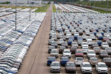 Volkswagen Group Rus, Russia, Kaluga  - MAY 24, 2020: Rows of a new cars parked in a distribution center on a cloudy day in the spring and a car factory buildings. Parking in the open air.のeditorial素材