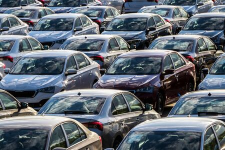 Rows of a new cars parked in a distribution center on a car factory on a sunny day. Top view to the parking in the open air.の写真素材