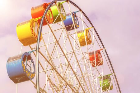 Ferris wheel with multi-colored cabs against the sky with clouds in the park on a sunny spring day.の写真素材