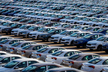 Volkswagen Group Rus, Russia, Kaluga - MAY 25, 2020: Rows of a new cars parked in a distribution center on a sunny day in the spring and a car factory buildings. Parking in the open air.のeditorial素材