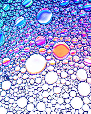 Colorful drops of oil on the water. Circles and ovals. Abstract bright background for design with reflection and refraction.の写真素材