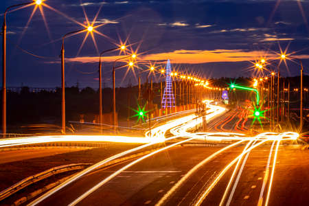 Traces of headlights from cars moving at night on the bridge, illuminated by lanterns. Abstract...