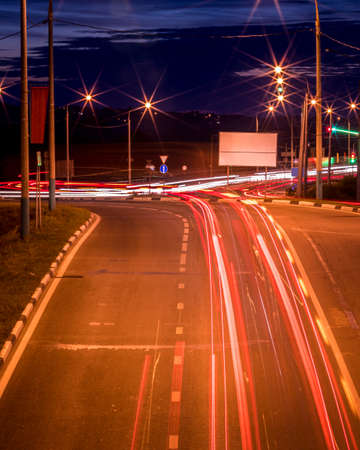 Traces of headlights from cars moving at night on the bridge, illuminated by lanterns. Abstract cityscape with highway at dusk.の写真素材