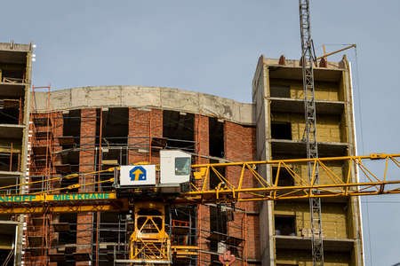 Fragment of an unfinished concrete and red brick building under construction with scaffolding and a...