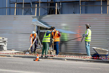 Russia, Kaluga - SEPTEMBER 16, 2020: A group of asian workers preparing the sidewalk for laying road tiles on a sunny day.のeditorial素材