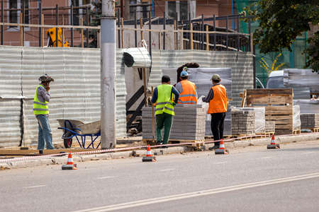 Russia, Kaluga - SEPTEMBER 16, 2020: A group of asian workers preparing the sidewalk for laying road tiles on a sunny day.のeditorial素材