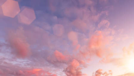 Colorful orange-purple dramatic clouds lit by the setting sun against the evening blue sky.の写真素材