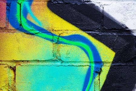 A fragment of colorful graffiti painted on a brick wall. Abstract background for design.