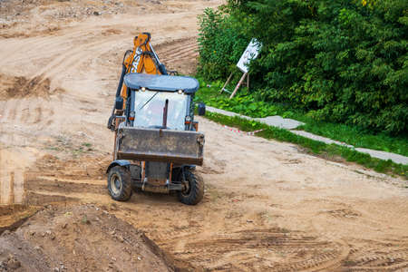 Russia, Kaluga - OCTOBER 27, 2020: Tractor with a bucket leveling a plot of land for road...
