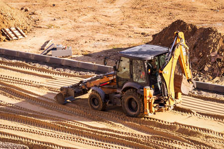 Russia, Kaluga - OCTOBER 27, 2020: Tractor with a bucket leveling sand for road construction.