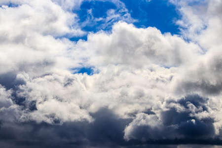 Bright blue sky with dramatic cumulus clouds lit by the daytime sun. Abstract background.の写真素材