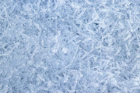 Top view of snow crystals illuminated by sunlight, shot close-up. Winter background.