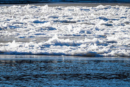 Melting ice floating on the river on a sunny spring day. Cracked ice texture.