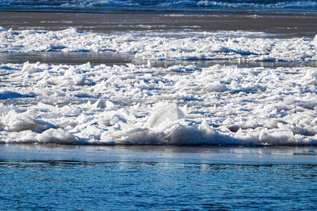 Melting ice floating on the river on a sunny spring day. Cracked ice texture.