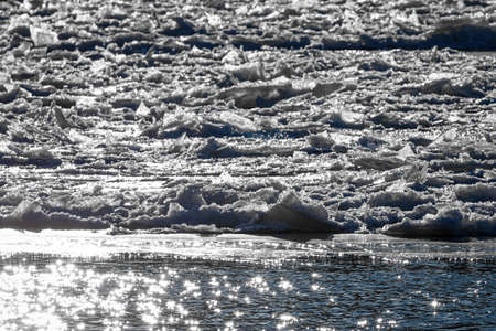 Melting ice floating on the river on a sunny spring day. Cracked ice texture.